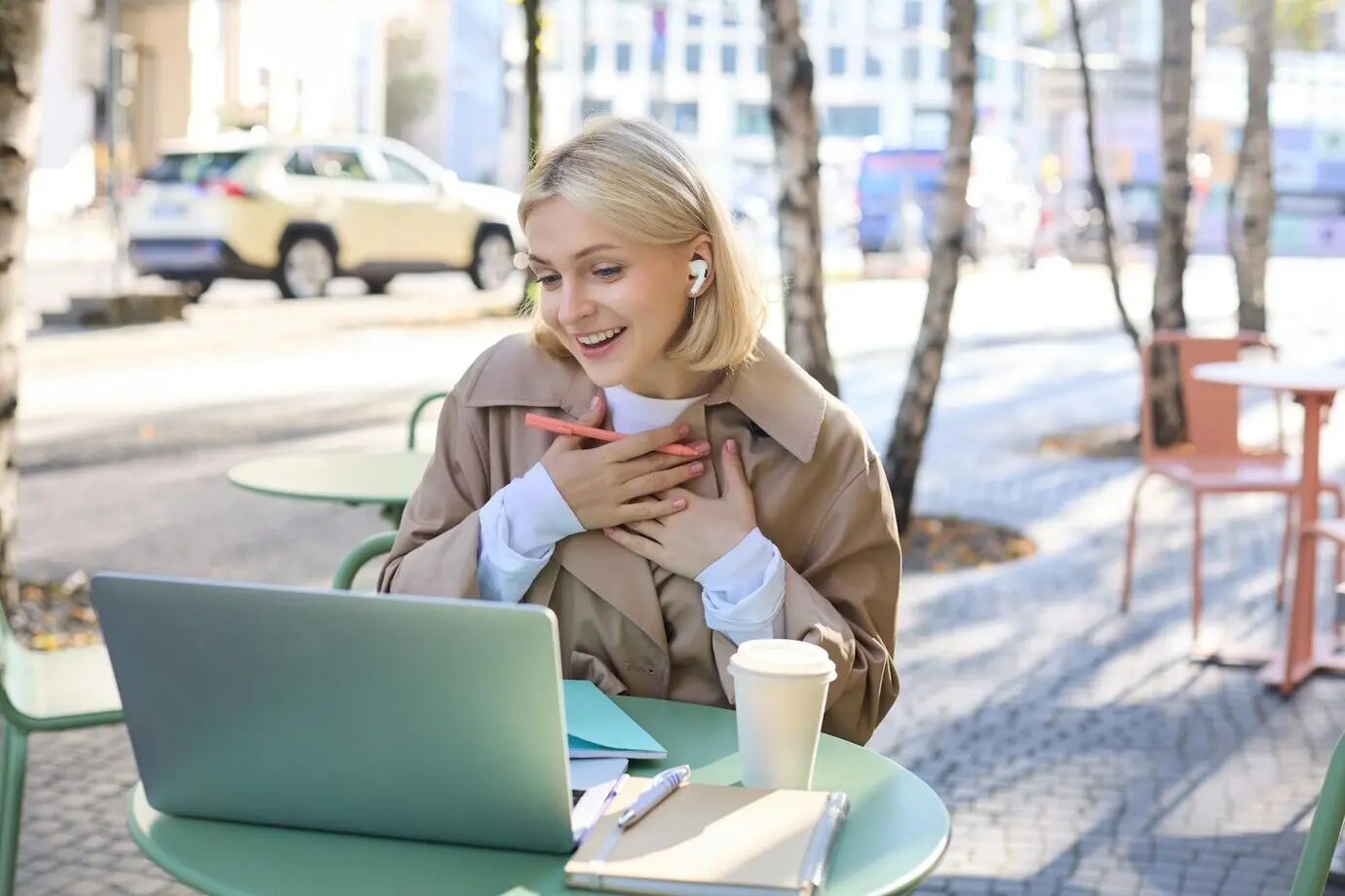 A lifestyle and technology concept depicting a young blond working woman in a trench coat, studying and working.